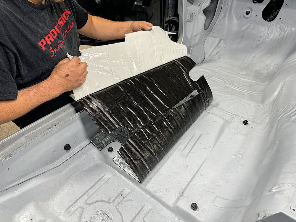 010 Technician peeling adhesive backing from insulation for Camaro’s interior installation copy