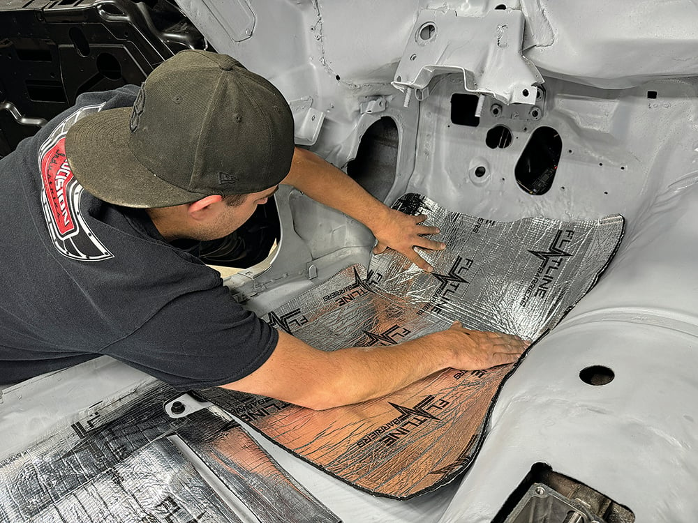 016 Technician pressing sound-deadening insulation onto the Camaro’s firewall area copy